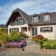 Leicht pinkes Einfamilienhaus mit einer grauen Coplaning Alu Haustür und grauen Coplaning Holz- Alu Fenster mit passenden Klappläden.