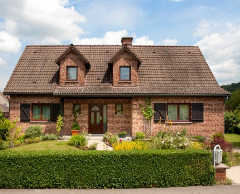 Einfamilienhaus mit Klinkerfassade mit einer braunen klassischen Coplaning Haustür und braunen Coplaning PVC Alu Fenster.