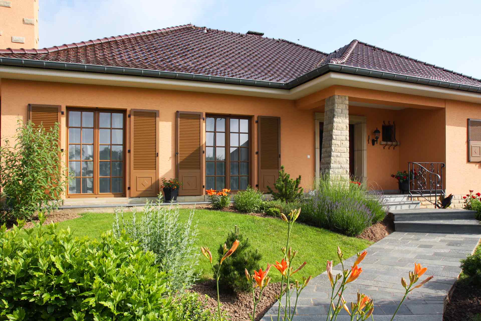 Oranges Einfamilienhaus mit Holz Alu Coplaning Fenster mit Klappläden und einer modernen Coplaning Haustür.