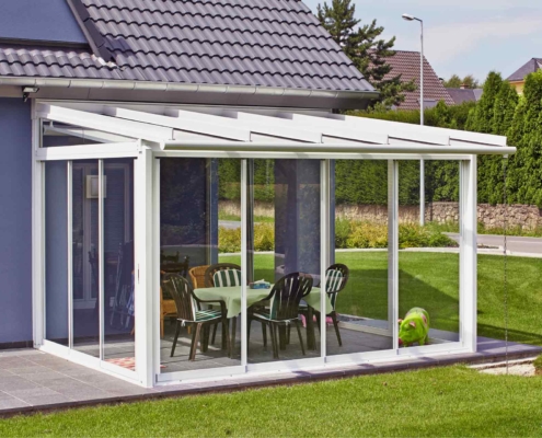 Lila Einfamilienhaus mit Nahaufnahme der Rückseite des Hauses mit Blick auf eine Coplaning Veranda Lichtoase mit weißer Glasfaltwand, Schiebefenster mit Glasdach und einer Innenmarkise mit Windschutz,