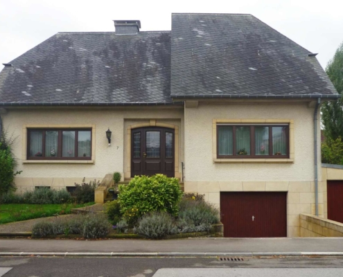 Weißes Einfamilienhaus mit neuer Bleiglas verglasten braunen Coplaning Holz Haustür.